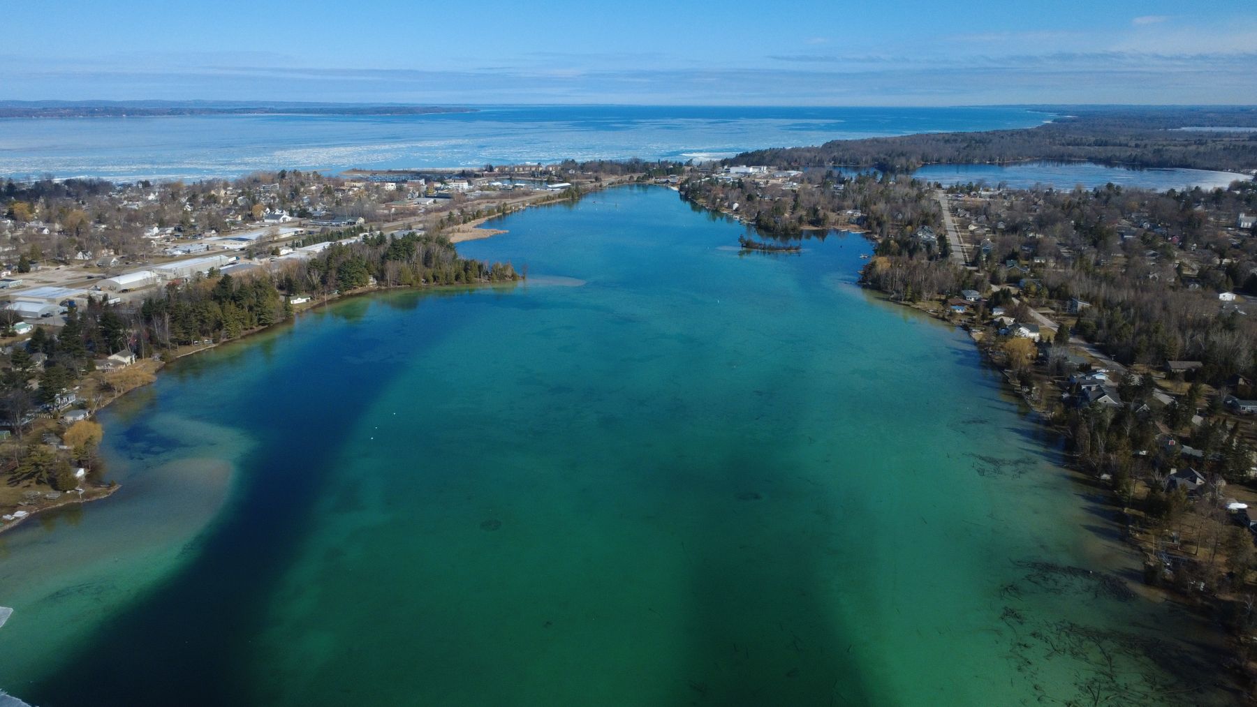 Aerial view of Torch Lake's blue-green water and the wooded shoreline of Antrim County, Michigan